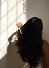 Load image into Gallery viewer, Women combing her hair with marble wide tooth comb under natural indoor sunlight
